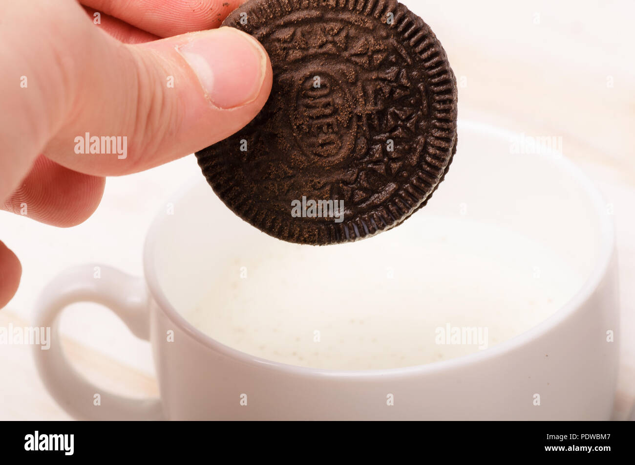 KRASNODAR, Russia - 17 Giugno 2018: Oreo cookie isolato in mano, dunk nel latte. Costituito da due wafer al cioccolato con un dolce ripieno di panna in betwe Foto Stock