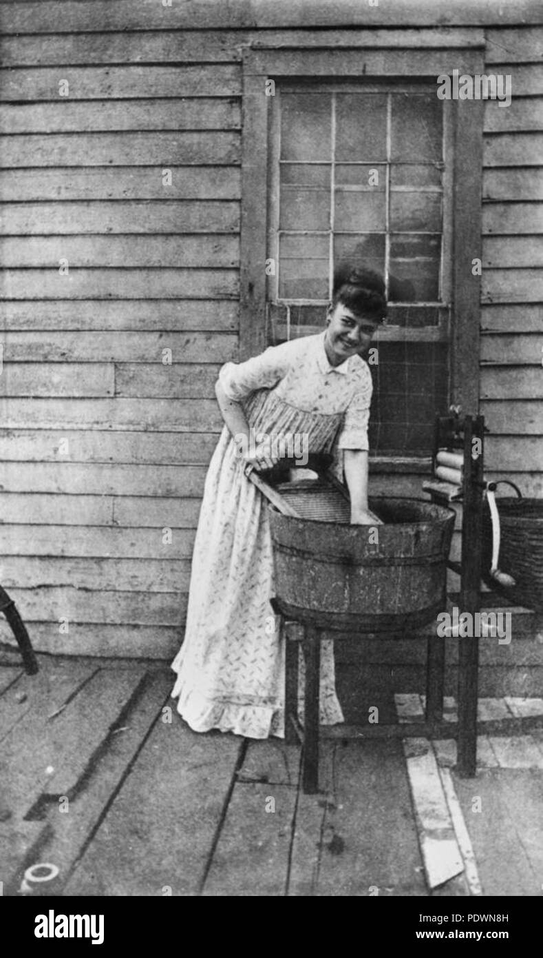 271 StateLibQld 1 70375 donna abiti handwashing sulla veranda di una casa, 1902-1904 Foto Stock