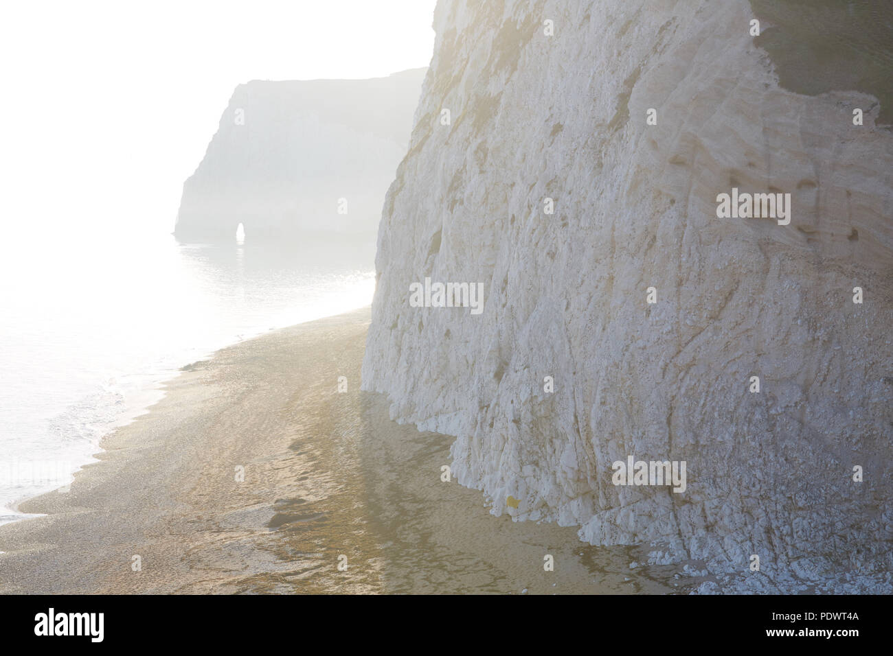 Un vago sunny immagine dalle scogliere erbose della Jurassic Coast a porta di Durdle, guardando in giù alla spiaggia di ciottoli a testa di pipistrelli Foto Stock