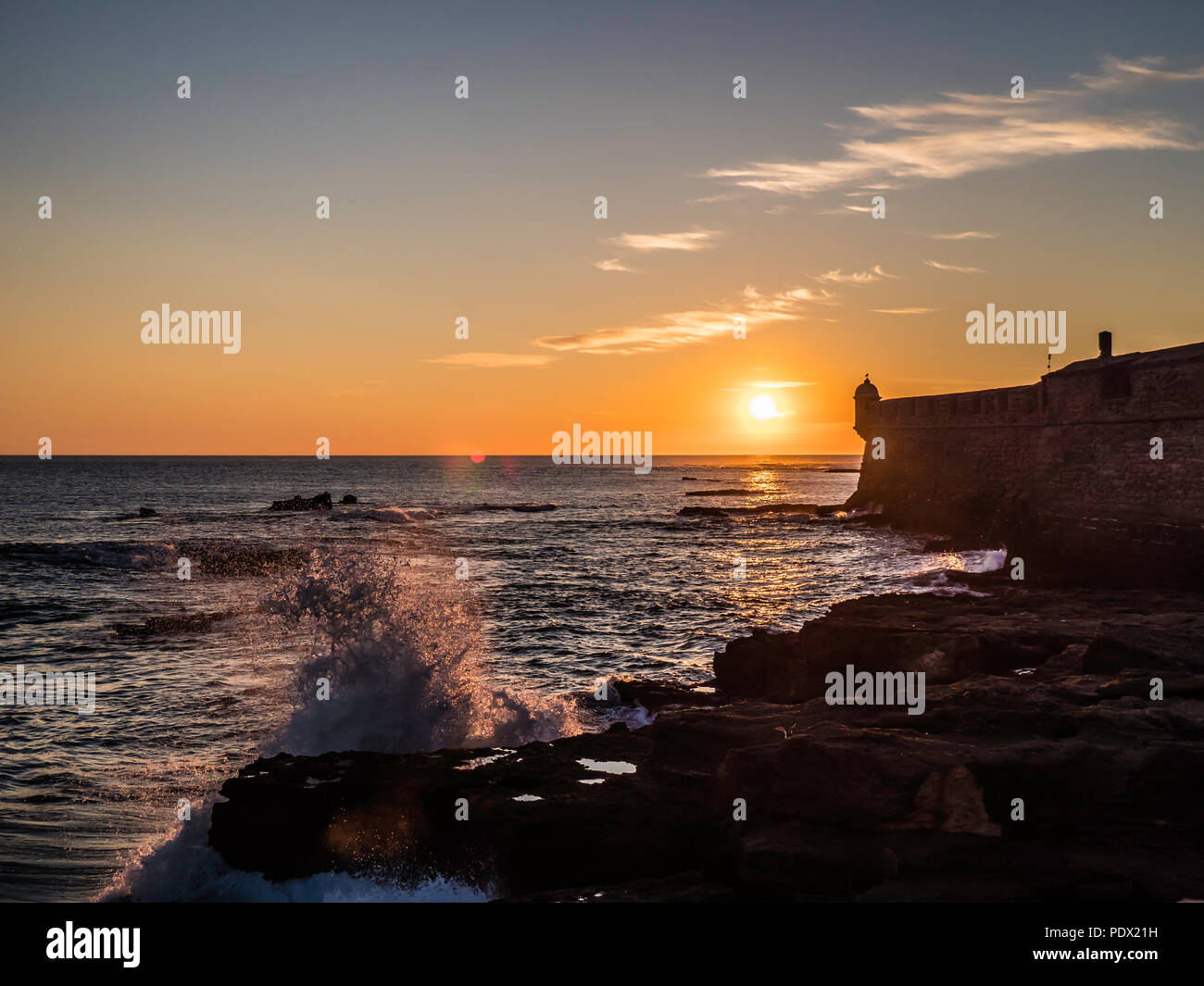 Onde drammatico di colpire la riva durante il tramonto Foto Stock