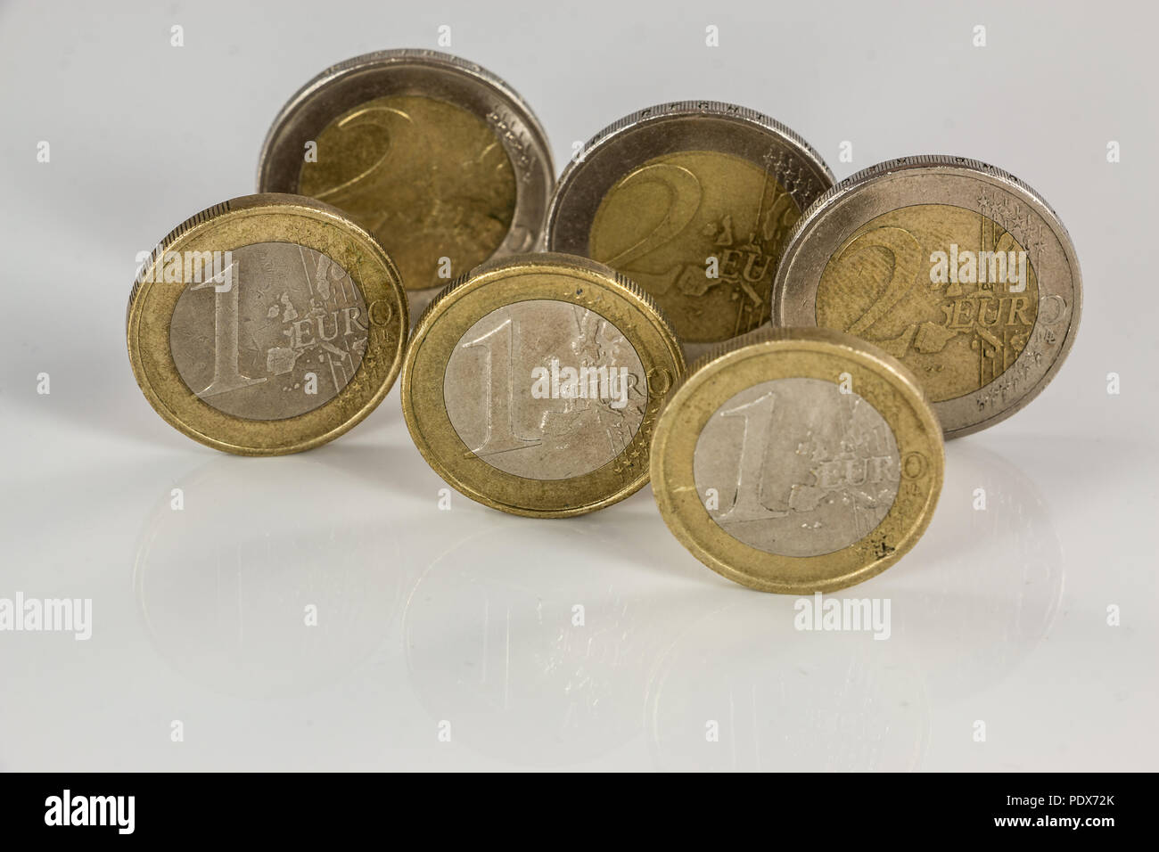 Monete metalliche in euro su sfondo bianco con riflessioni Foto Stock