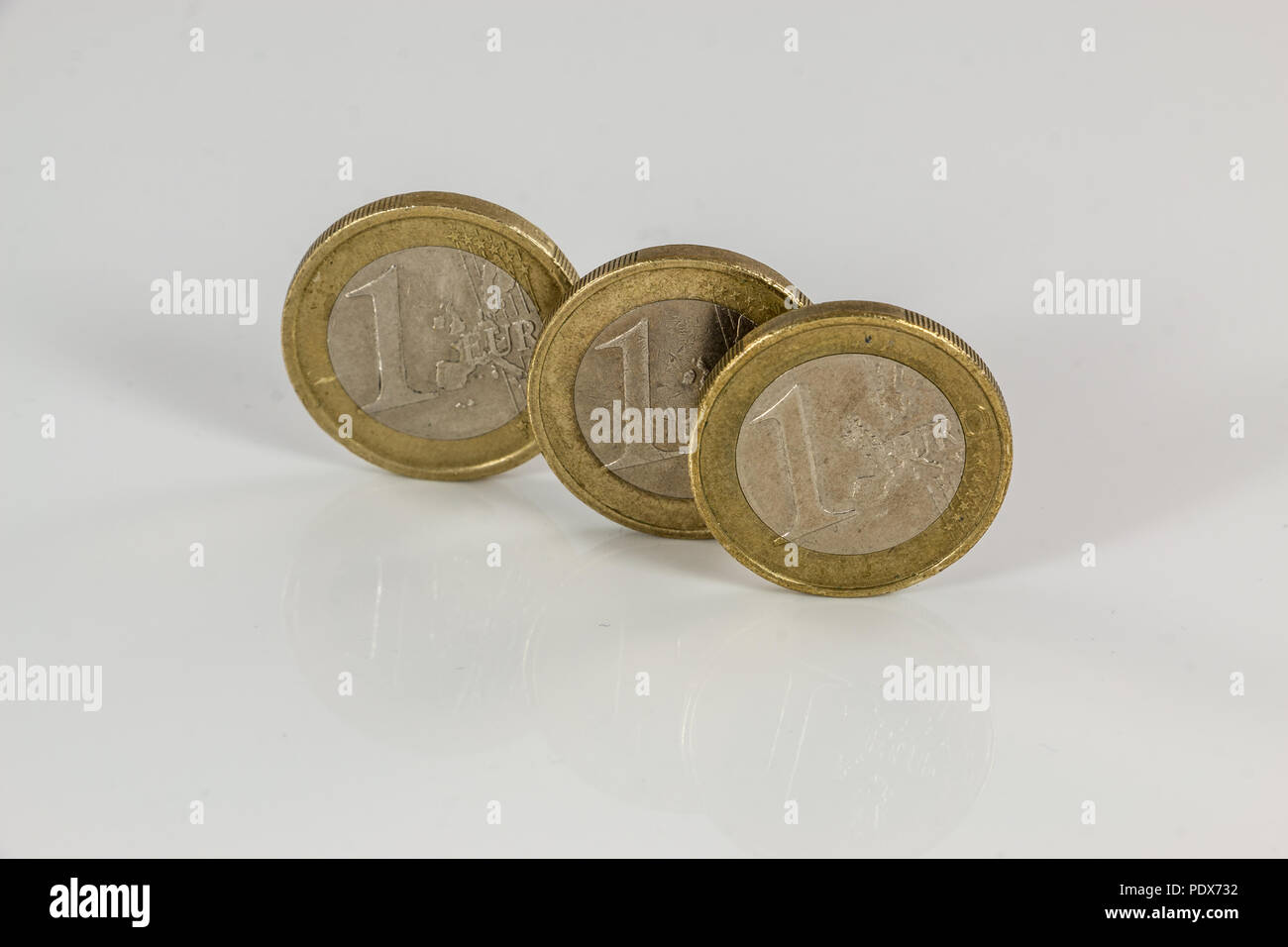 Monete metalliche in euro su sfondo bianco con riflessioni Foto Stock