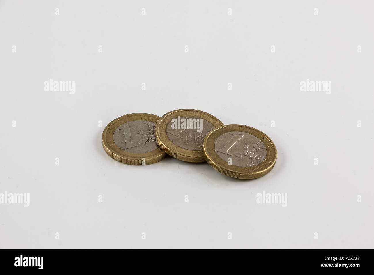 Monete metalliche in euro su sfondo bianco con riflessioni Foto Stock