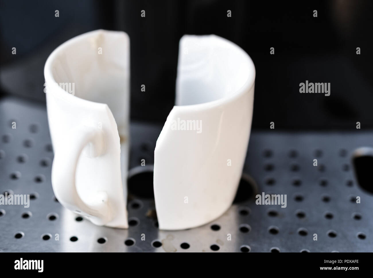 Close up su bianco tazza di caffè rotto in metà posto sulla home macchina espresso. Concetto di bad mattina Foto Stock