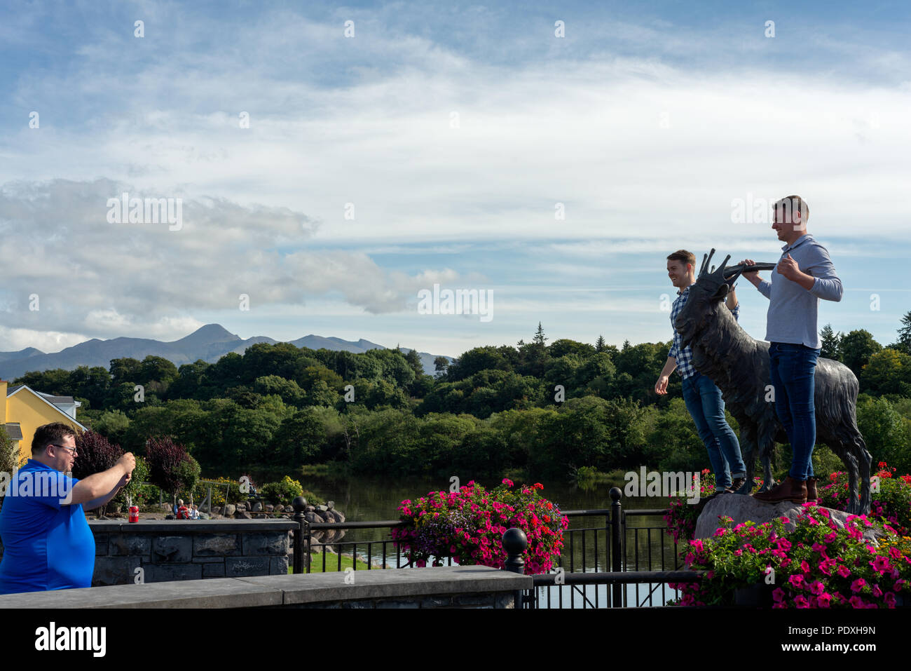 Turisti australiani divertirsi mentre si scattano foto con il re Puck statua durante il Puck Fair - Irlanda più antica fiera tradizionale. Irish summer festival fiera. Killorglin, nella contea di Kerry, Irlanda. Foto Stock