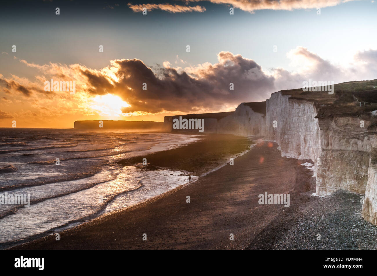 Birling Gap, East Sussex, Regno Unito..10 agosto 2018..Sun attraversa la nuvola al tramonto dopo una giornata di pioggia scura sulla costa meridionale con vento forte dal Sud degli Stati Uniti. A causa del lungo caldo secco incantesimo e ora pioggia le scogliere di gesso sono più instabili con molte rockFalls. Foto Stock