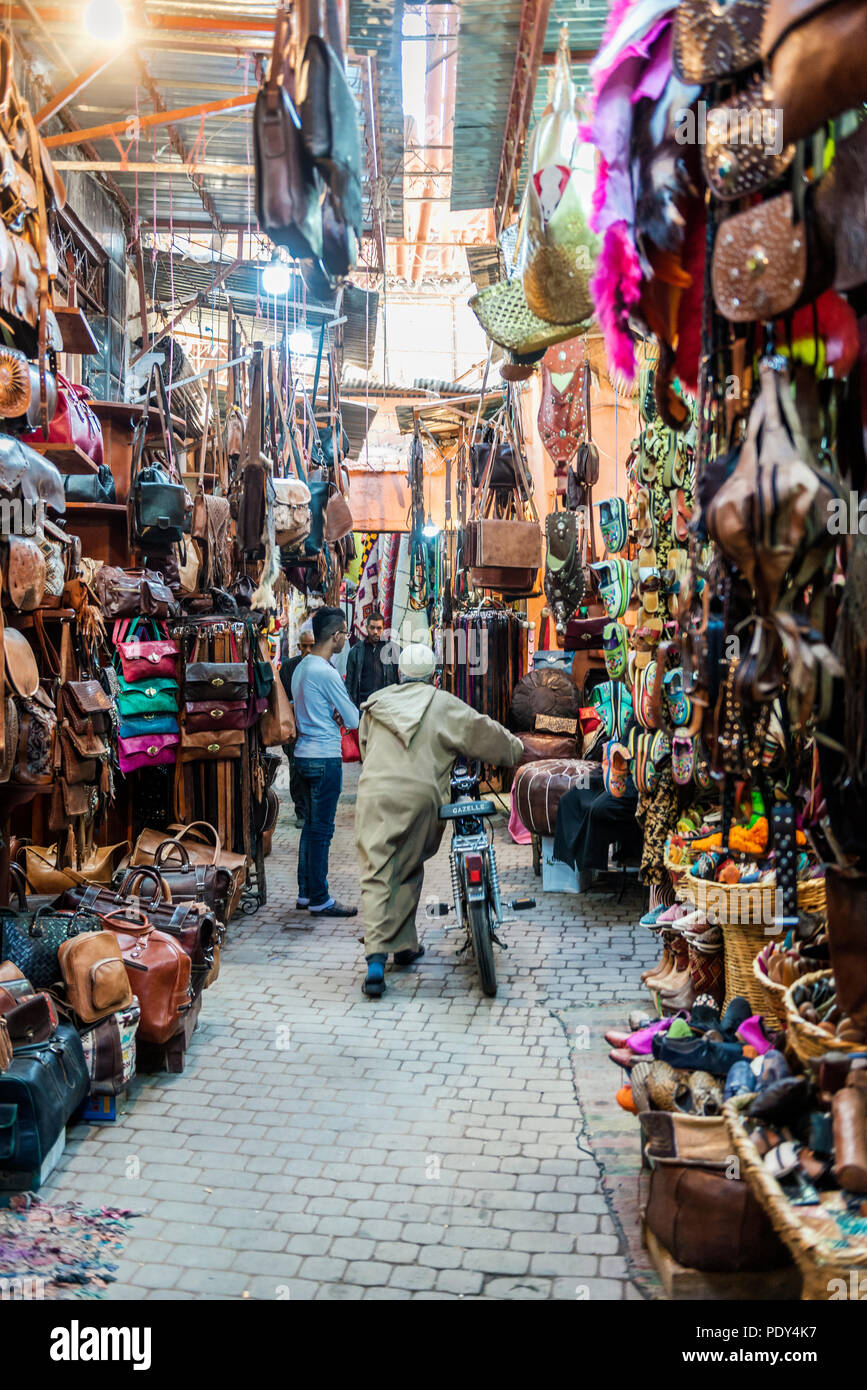 Locale con un motociclo, strade strette con i prodotti in cuoio in un mercato arabo, Shouk, Fez Medina di Fez, Marocco Foto Stock