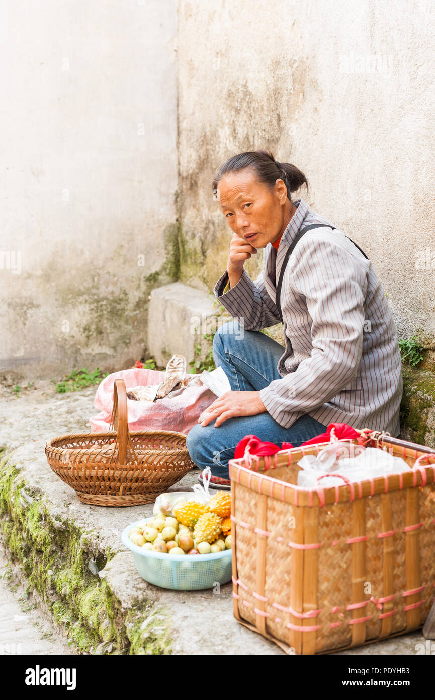 Hongcun Village, Cina - 18 ottobre 2014. Donna vendita di verdure, carni e spezie, visualizzata al di fuori di un piccolo negozio. Sapori locali ed esotiche fo Foto Stock