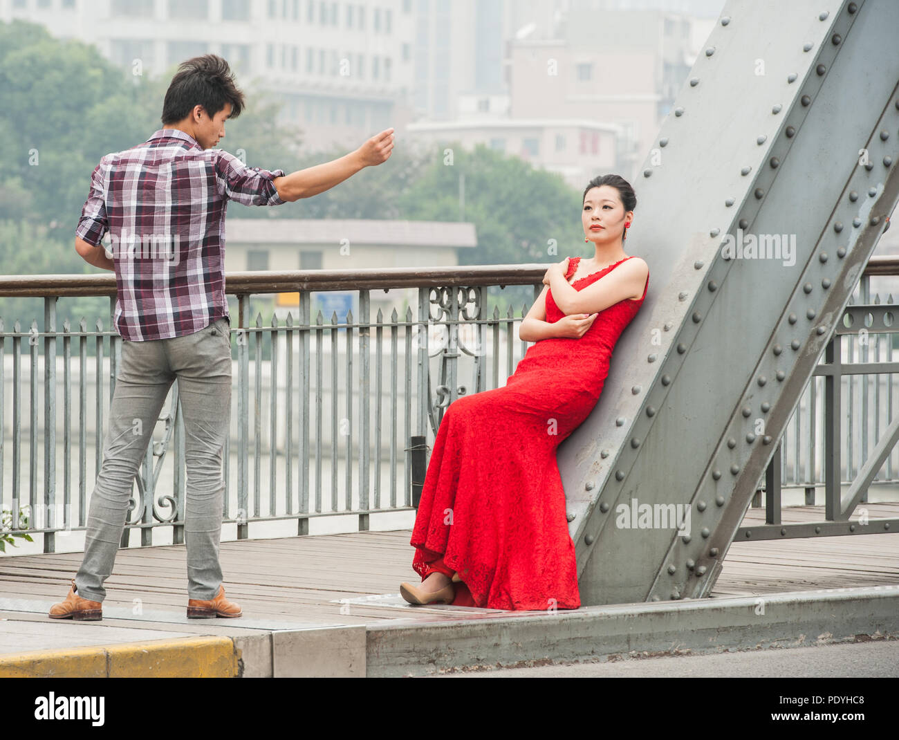 Shanghai, Cina - 20 ottobre 2014. Fotografo e una moda femminile modello durante un servizio fotografico su un ponte sopra il fiume Huangpu a Shanghai. Foto Stock