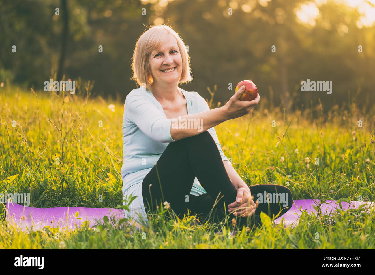 Ritratto di active senior donna mangiare apple dopo esercizio.Immagine è intenzionalmente tonica. Foto Stock