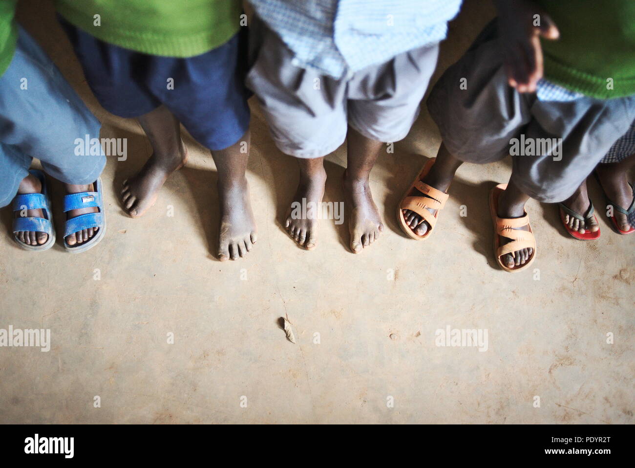 I giovani ugandesi Africana/scolari provare su scarpe usate dato per la scuola come un dono da parte del Regno Unito Foto Stock
