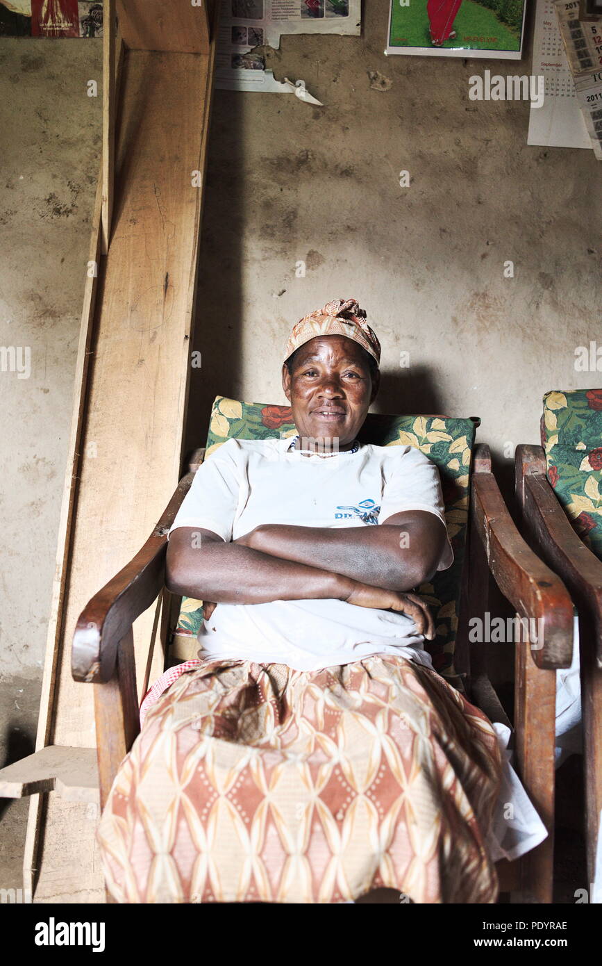 Donna ugandese a casa, in Uganda rurale, fissando la macchina fotografica. Cercando di lavorare da casa e sui campi, facendo dei soldi. Campagna Foto Stock