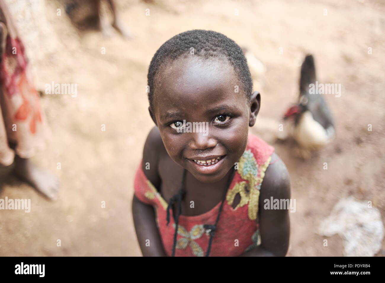 Giovane ragazza africana guarda nella telecamera con un grazioso vivace sorriso sul suo viso Foto Stock