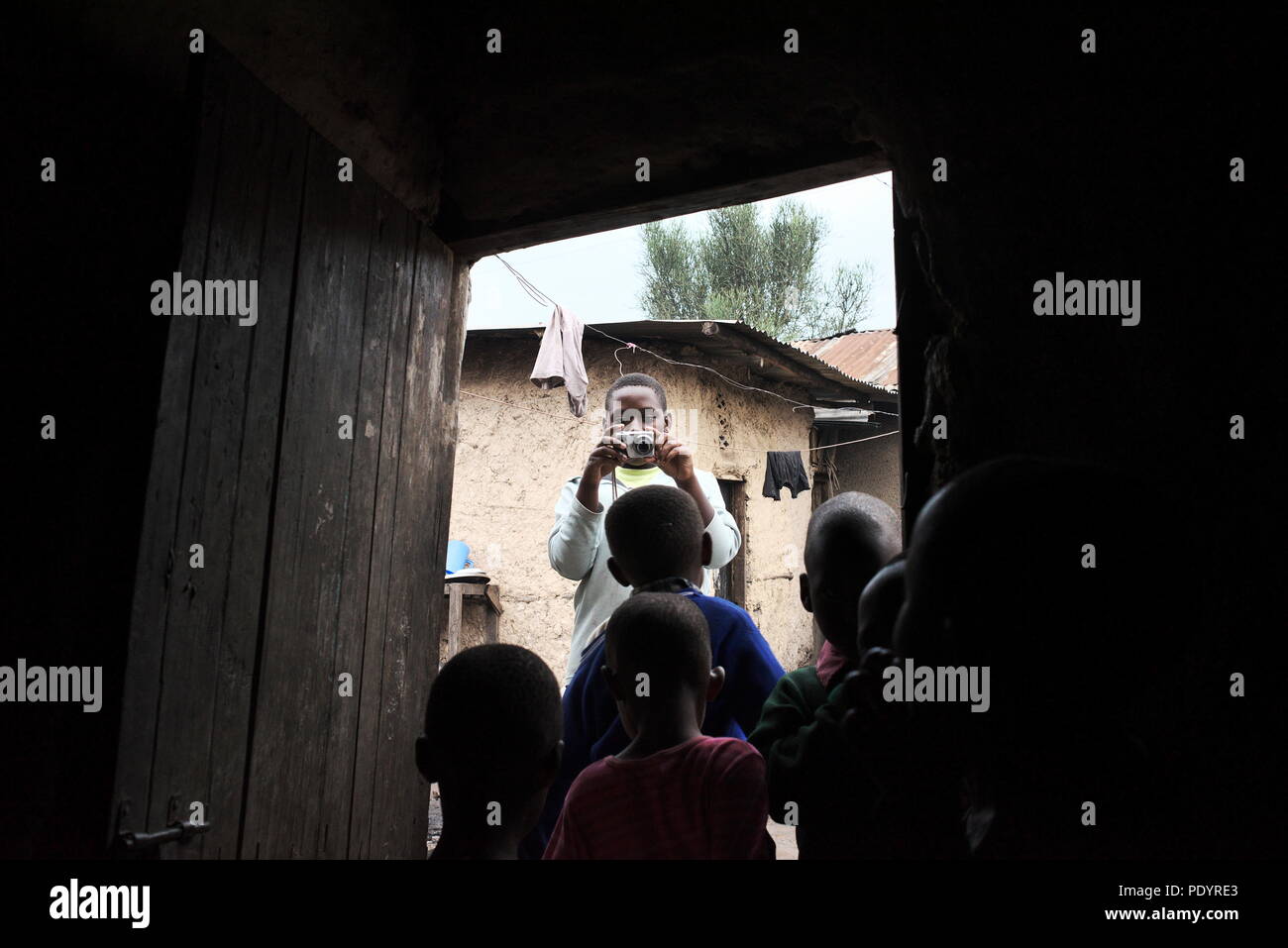 Giovane ragazza ugandese scatta una fotografia della sua famiglia nella comunità locale Foto Stock