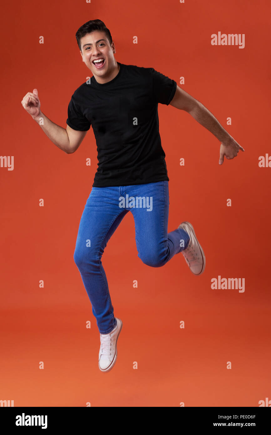 Casual giovane uomo jumping isolati su studio sfondo arancione Foto Stock