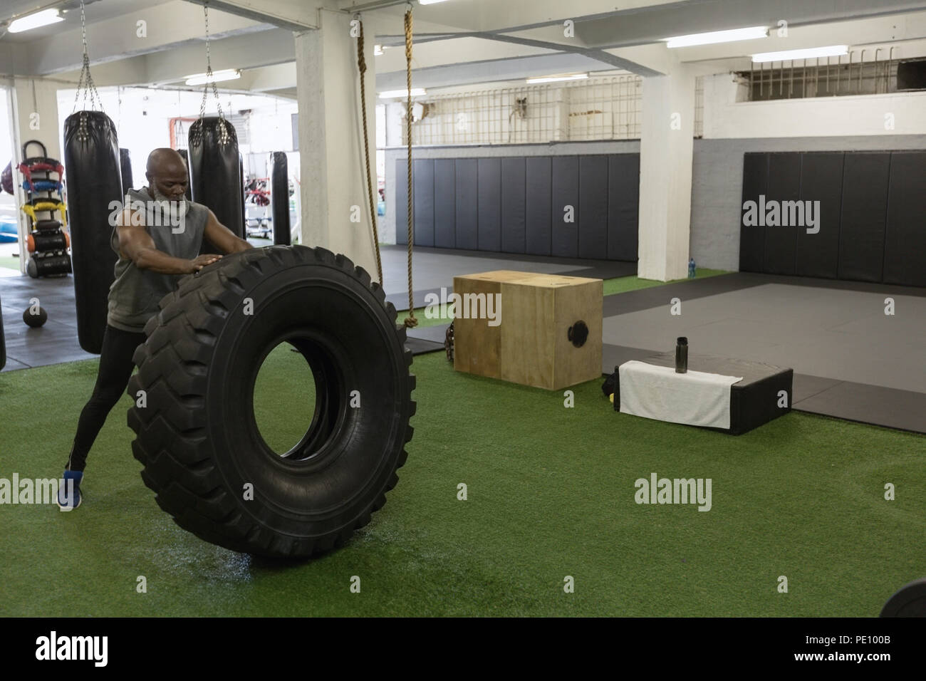 Senior uomo facendo crossfit pneumatico flip in studio fitness Foto Stock