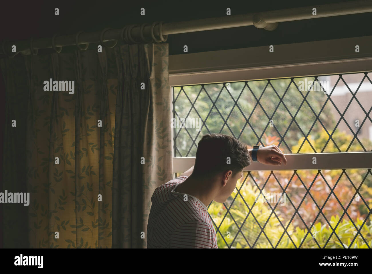 Uomo che guarda attraverso la finestra Foto Stock