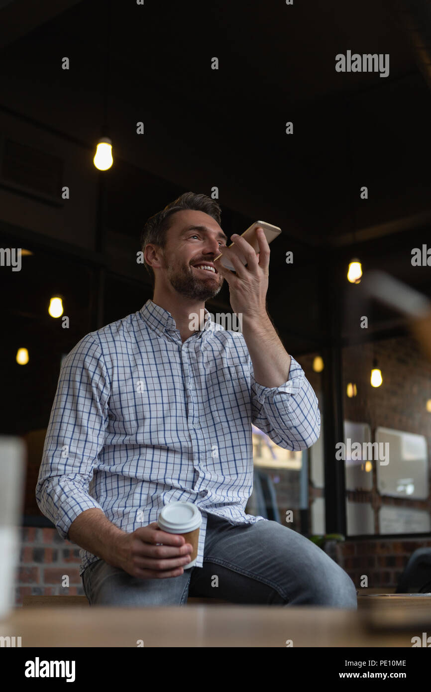 Executive maschio con caffè parlando al telefono cellulare Foto Stock