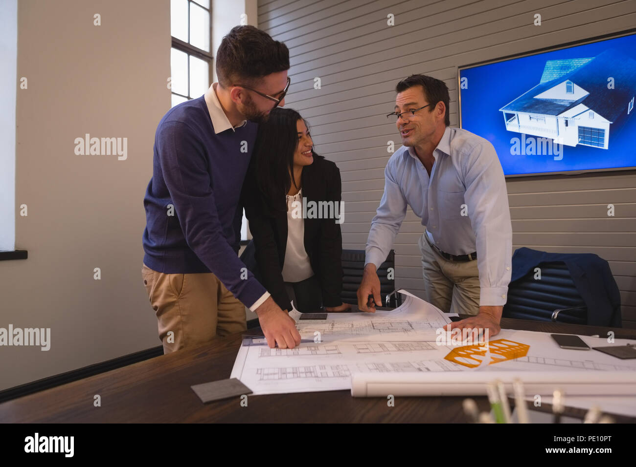 Colleghi di lavoro discutendo su blueprint in sala riunioni Foto Stock