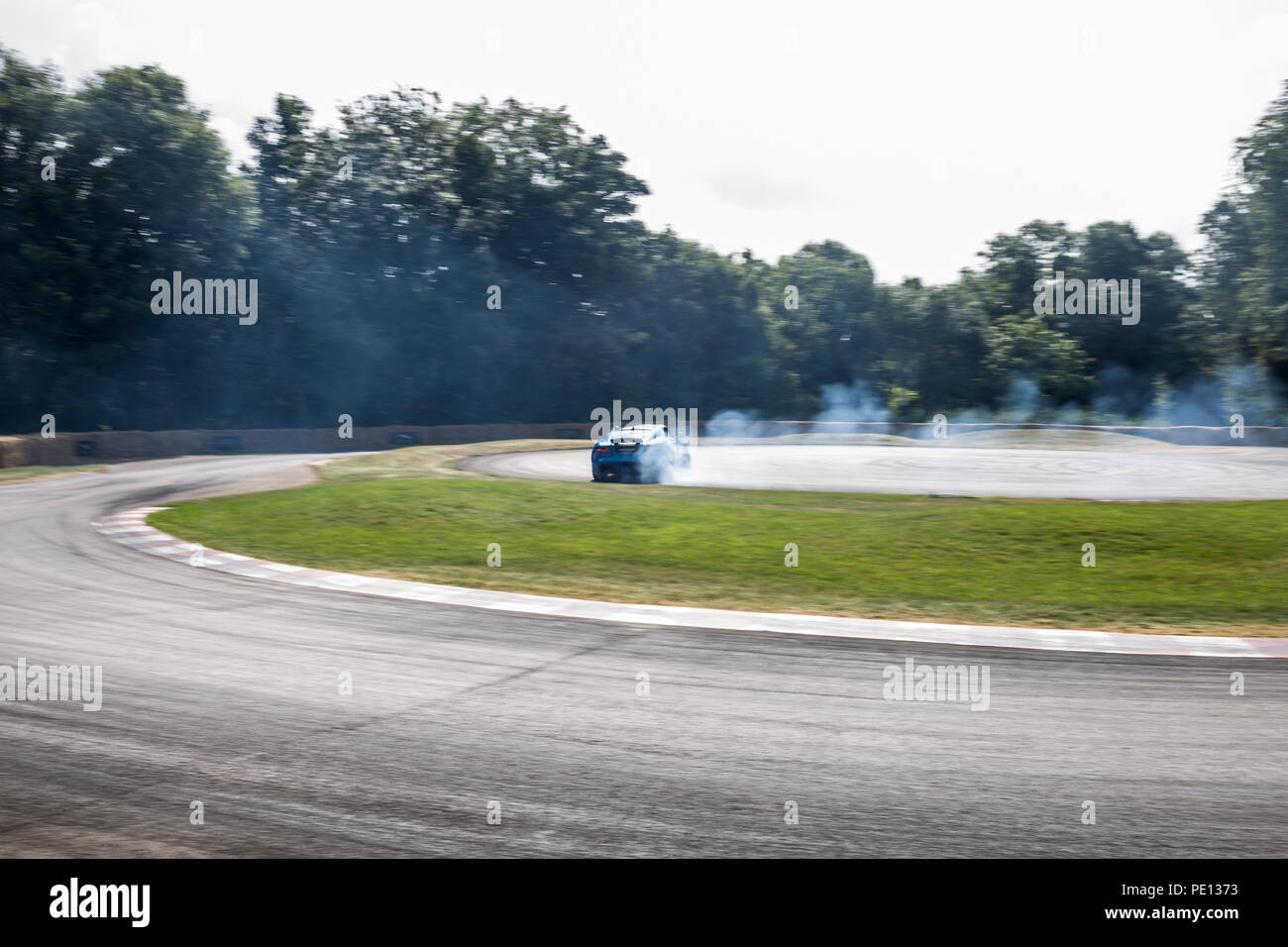 Una Jaguar sportscar gira i suoi pneumatici, creazione di fumo, su una pista a Goodwood Festival of Speed 2018. Foto Stock