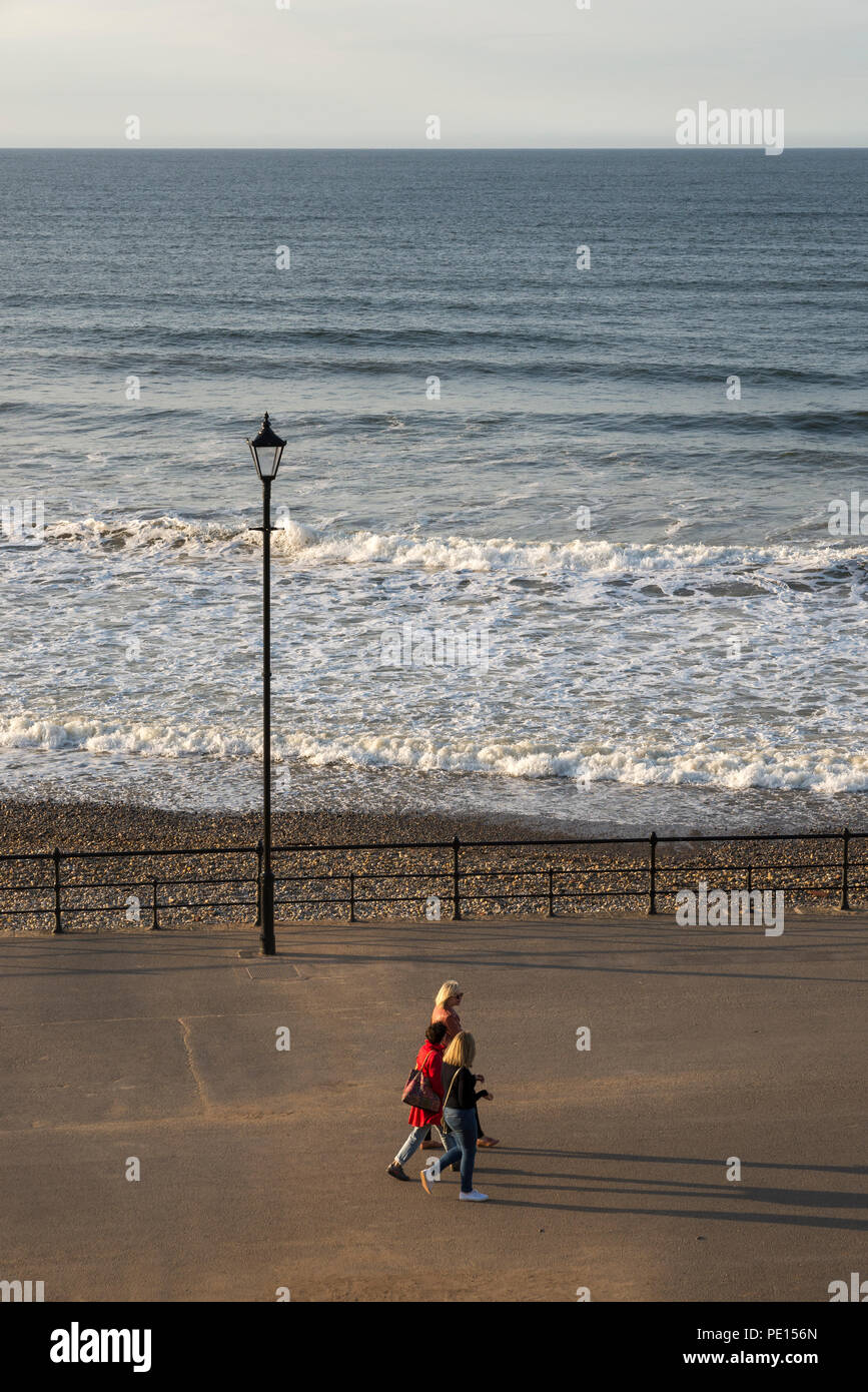 Il gruppo di amici di sesso femminile avente una chat come essi a piedi lungo la passeggiata di cambs, North Yorkshire, Inghilterra. Foto Stock