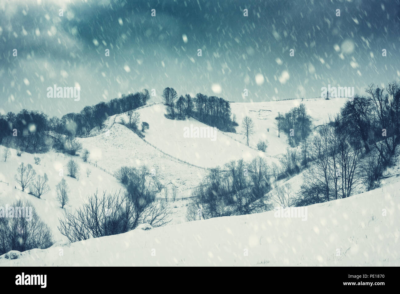 Drammatico paesaggio invernale, pendio di montagna durante la bufera di neve. Holiday sfondo, immagine vintage Foto Stock