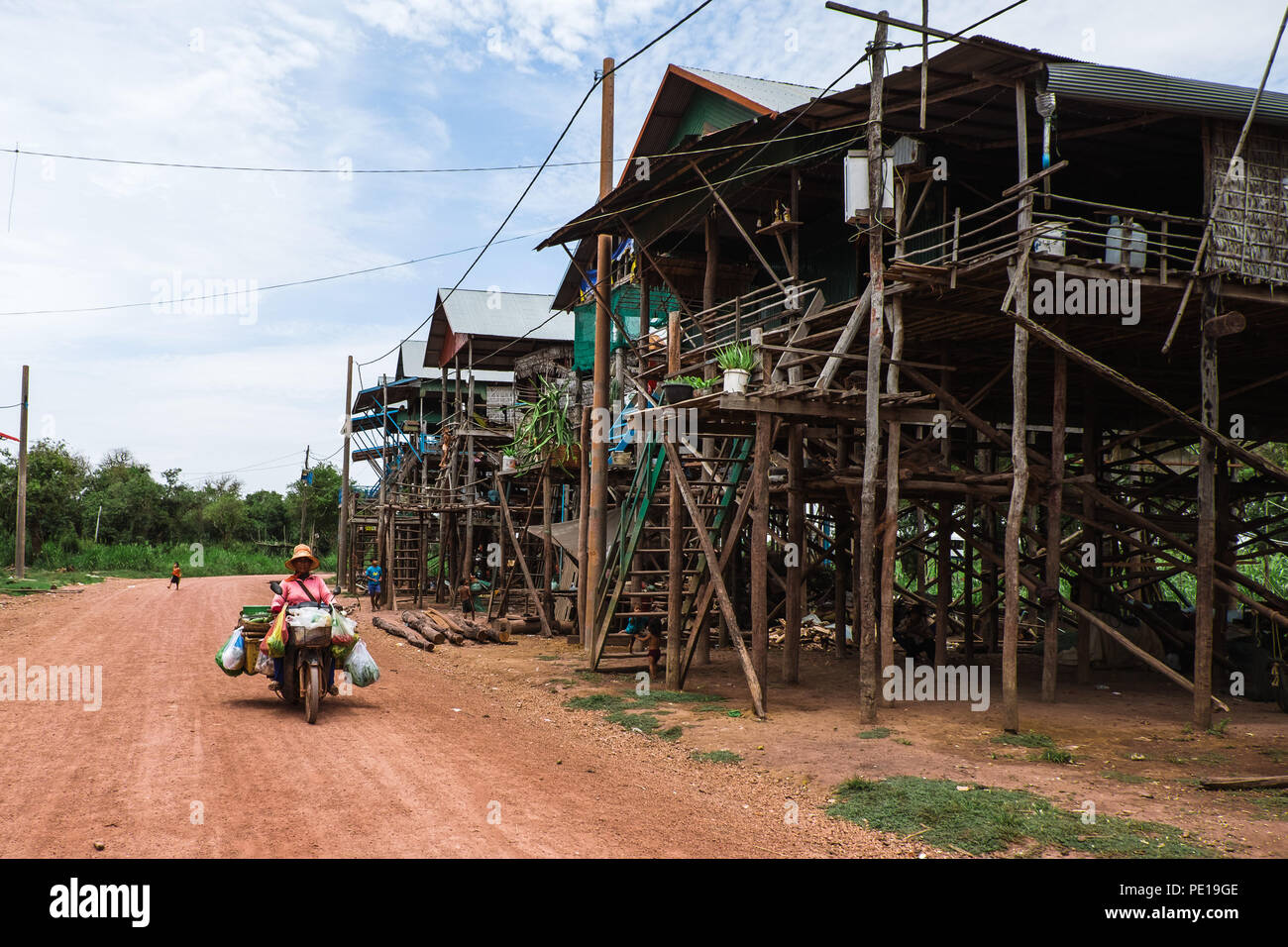 Una donna su un caricato fino a un motociclo in Kampong Phluk, uno della Cambogia "villaggi galleggianti' di Tonle Sap, durante la stagione secca. Foto Stock