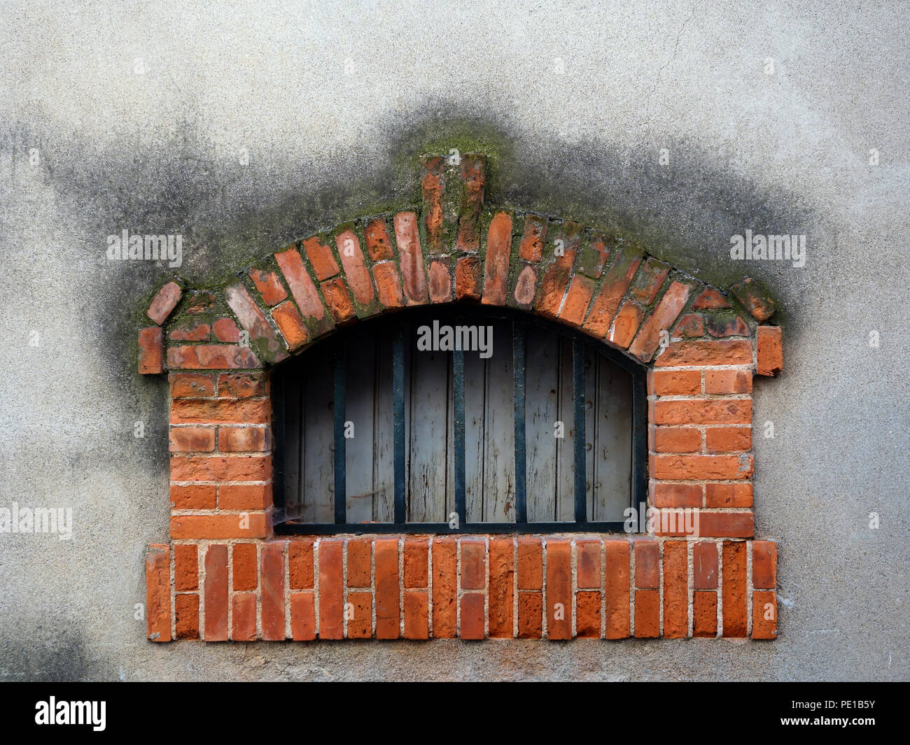 Parte superiore a forma di cupola piccola finestra cantina in mattoni surround sul reso a parete con forte le barre di sicurezza in Cessenon-sur-Orb, Francia Foto Stock