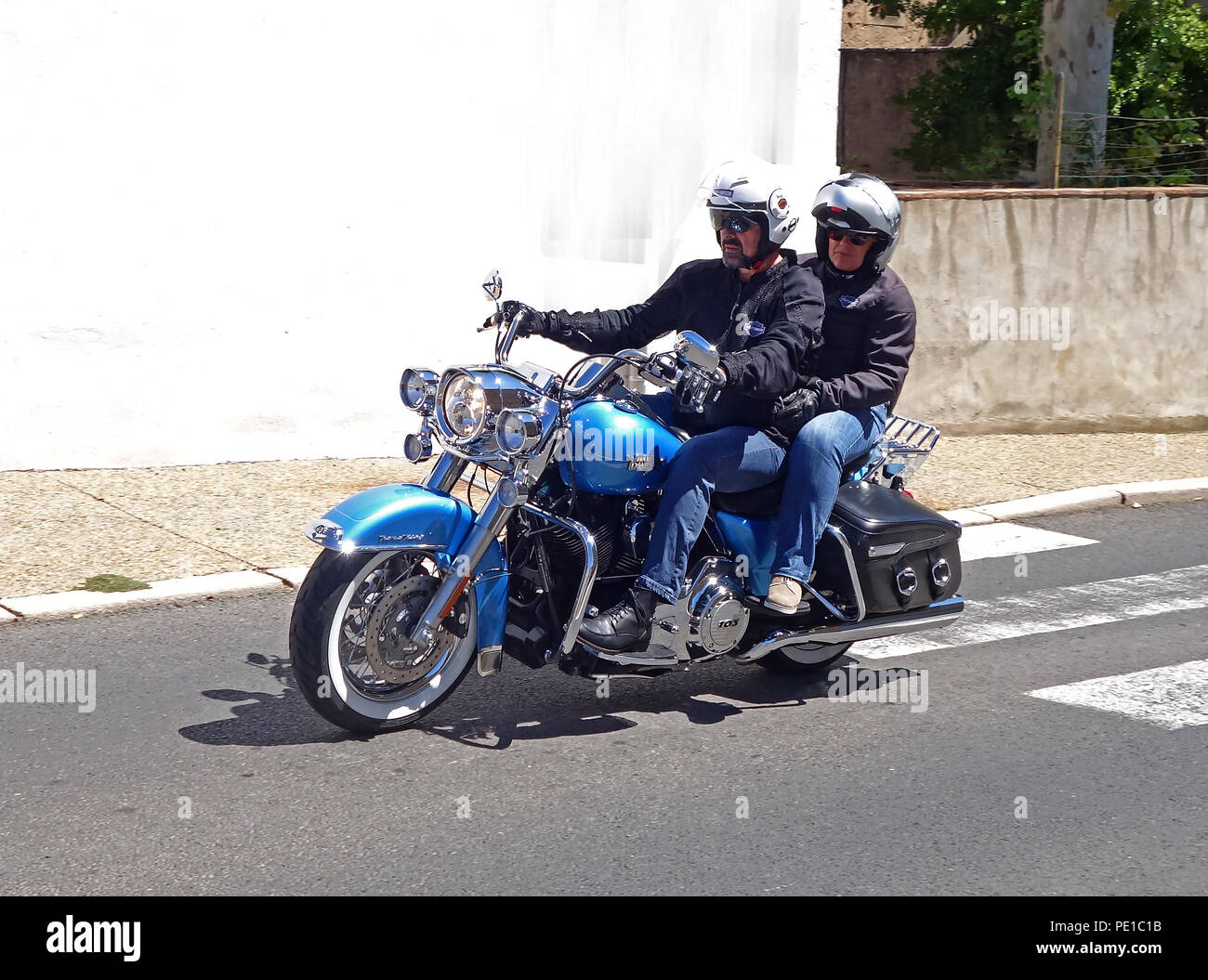 Pilota e i suoi passeggeri in sella ad una immacolata Blue Harley Davidson Road King FLHRC moto nel Cessenon-sur-Orb, Francia Foto Stock
