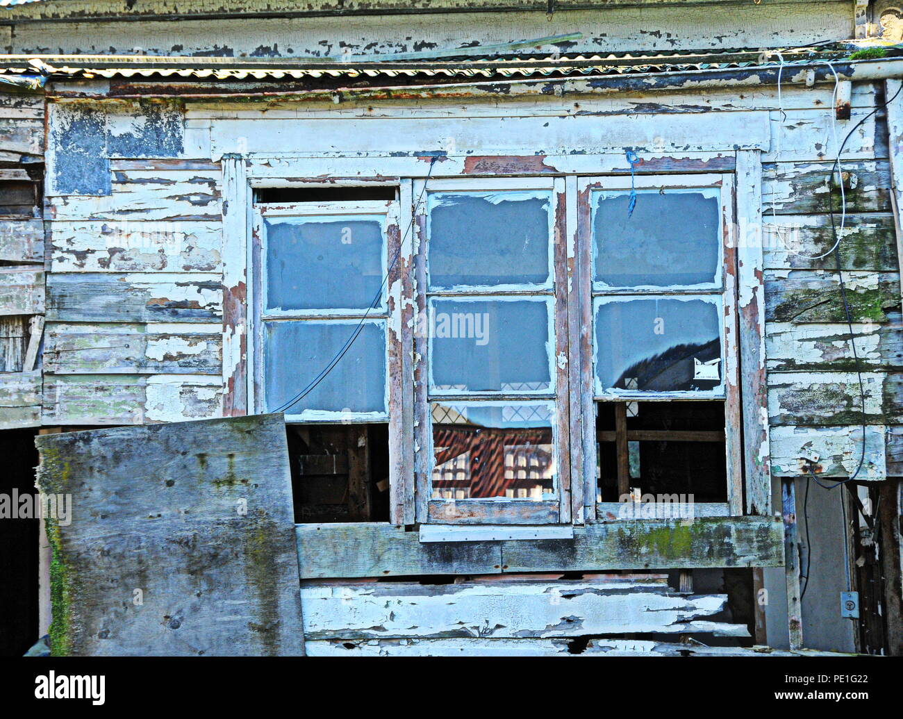 Il lato di una casa in legno abbandonata con nove finestre Foto Stock