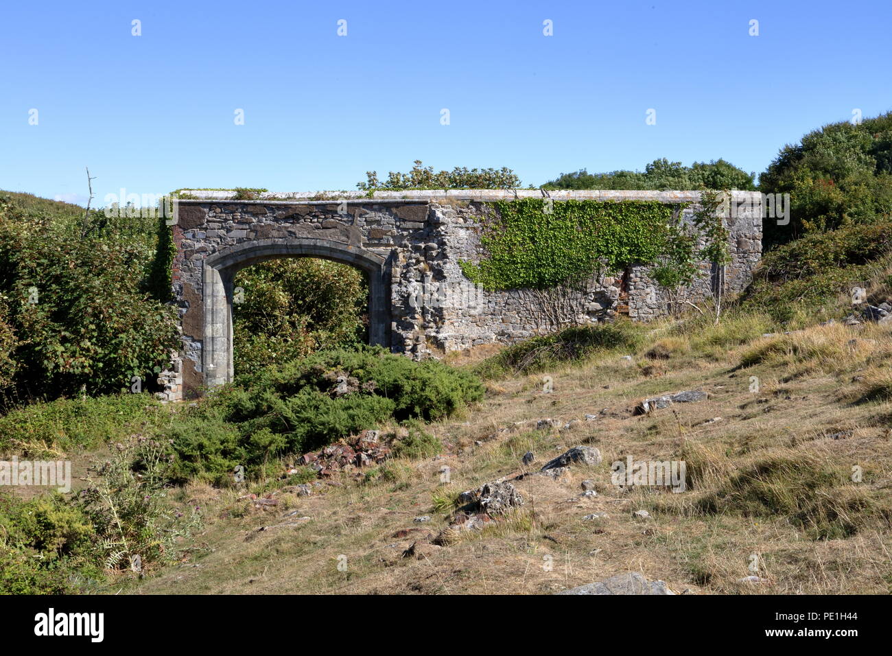 Una vecchia pietra isolata parete di ingresso a quello che una volta era un grande castello in alto su una collina dalla costa in una zona bellissima. Foto Stock