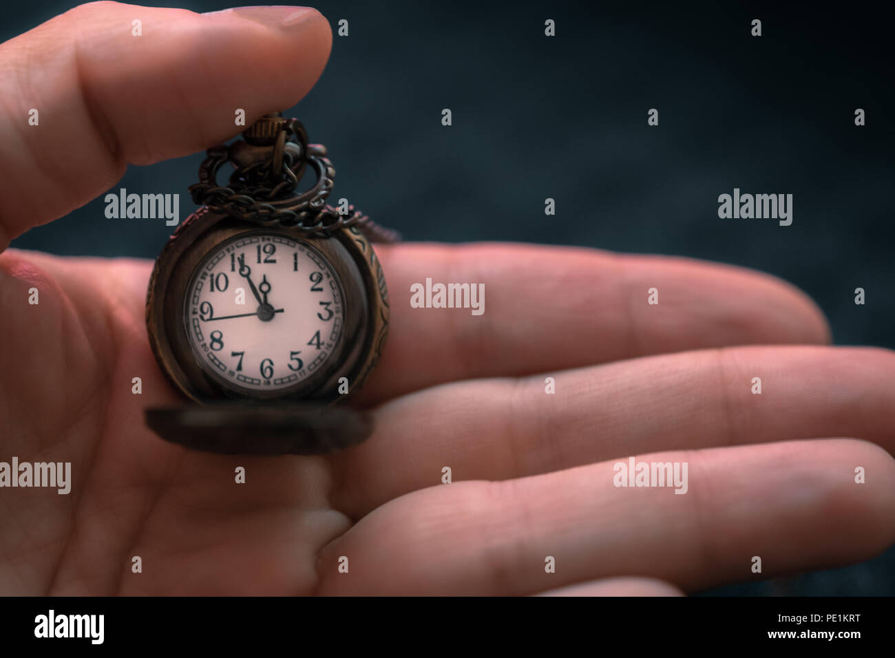 Mano che tiene un orologio da tasca con il tempo che mostra come cinque a ore dodici, concetto di tempo Foto Stock