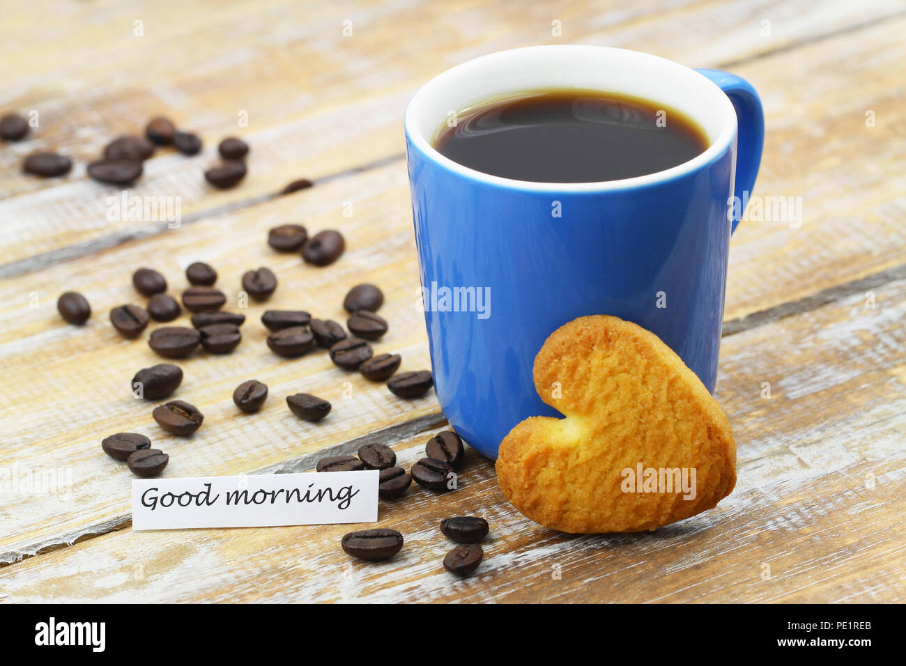 Buona mattina con carta a forma di cuore ad cookie appoggiata contro la tazza da caffè Foto Stock