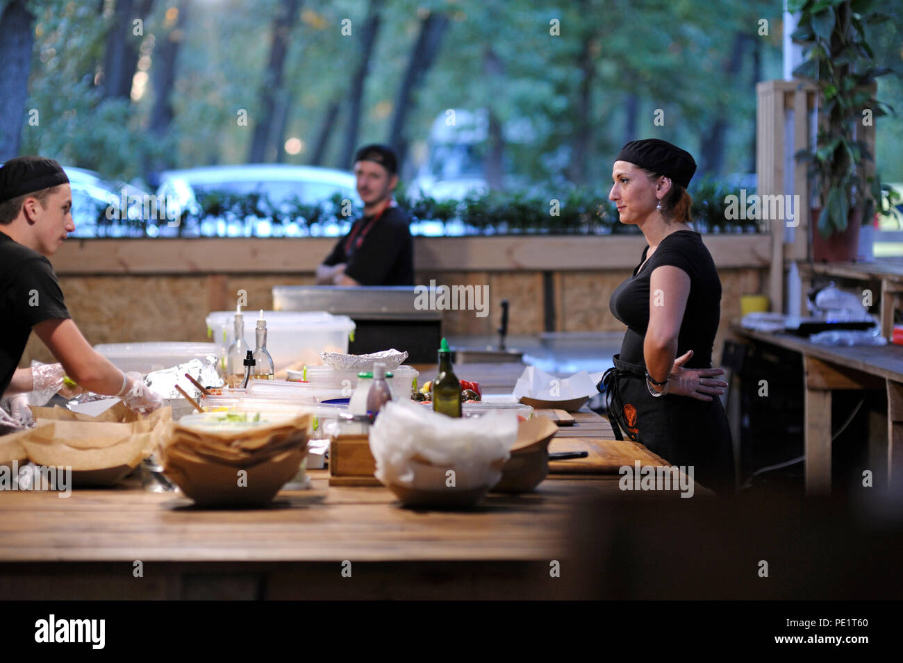 Cameriere e cameriera di comunicare durante la preparazione di pasti veloci su un tavolo da cucina di un ristorante. Il 25 luglio 2018. A Kiev, Ucraina Foto Stock