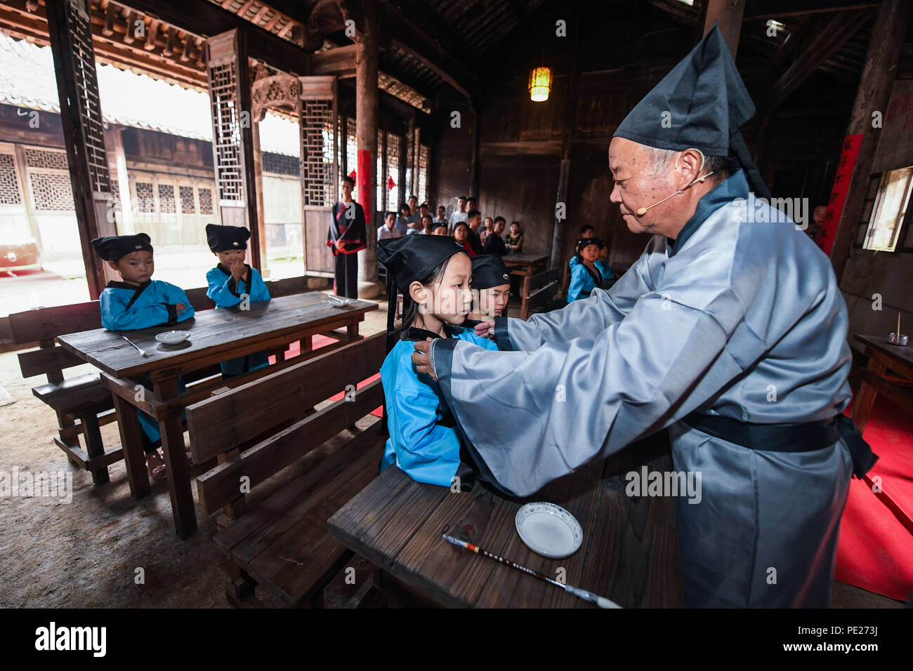 Changxing cinese della provincia dello Zhejiang. 12 Ago, 2018. Un insegnante organizza i vestiti per gli studenti di un vecchio-stile scuola privata nel villaggio di Zhongshan nella contea di Changxing, est della Cina di Provincia dello Zhejiang, Agosto 12, 2018. Credito: Xu Yu/Xinhua/Alamy Live News Foto Stock