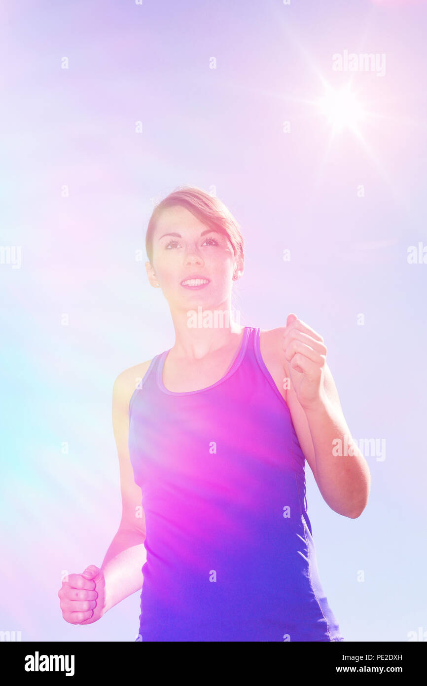 Giovane donna jogging all'aperto sotto il sole cielo blu Foto Stock