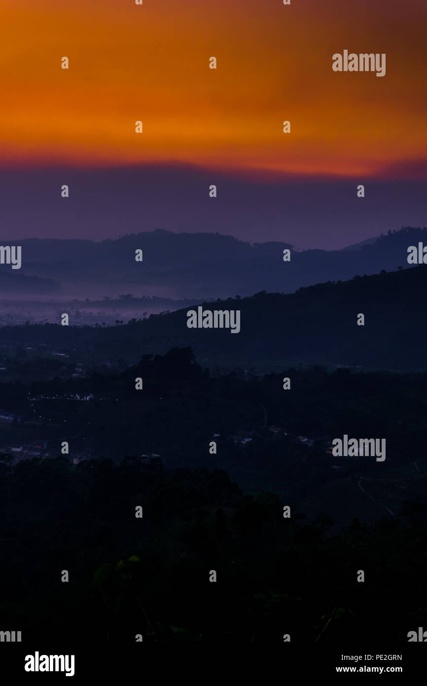 Strato di montagna e la nebbia sullo sfondo di un paesaggio con viola e toni di colore arancione Foto Stock