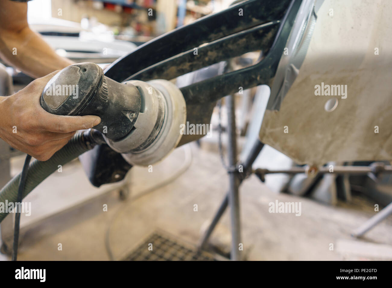Il meccanico lavora con una macchina di molatura. La pittura di Garage auto di servizio. Riparazione di sezione auto dopo l'incidente. Foto Stock