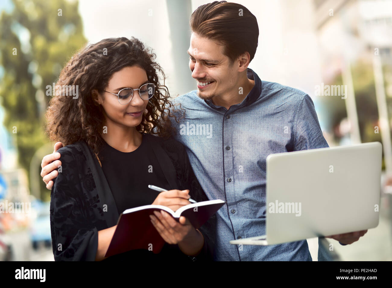 Business uomo e donna che lavorano su laptop insieme sulla costruzione di sfondo in città outdoor sentirsi felice. Foto Stock