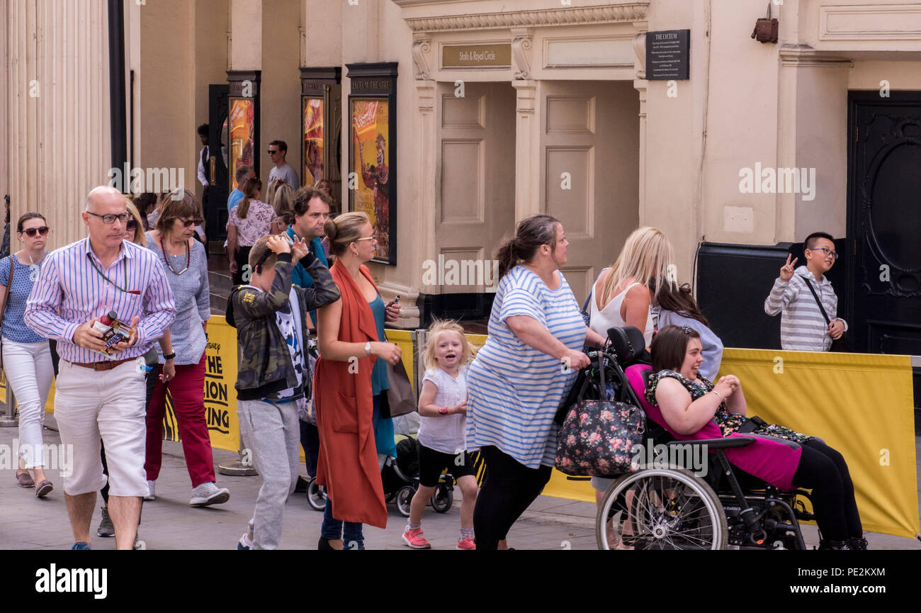 Trambusto e il traffico di persone a piedi teatro passato, giovane ragazzo dietro la barriera del teatro che dà segno di pace. London, England, Regno Unito Foto Stock