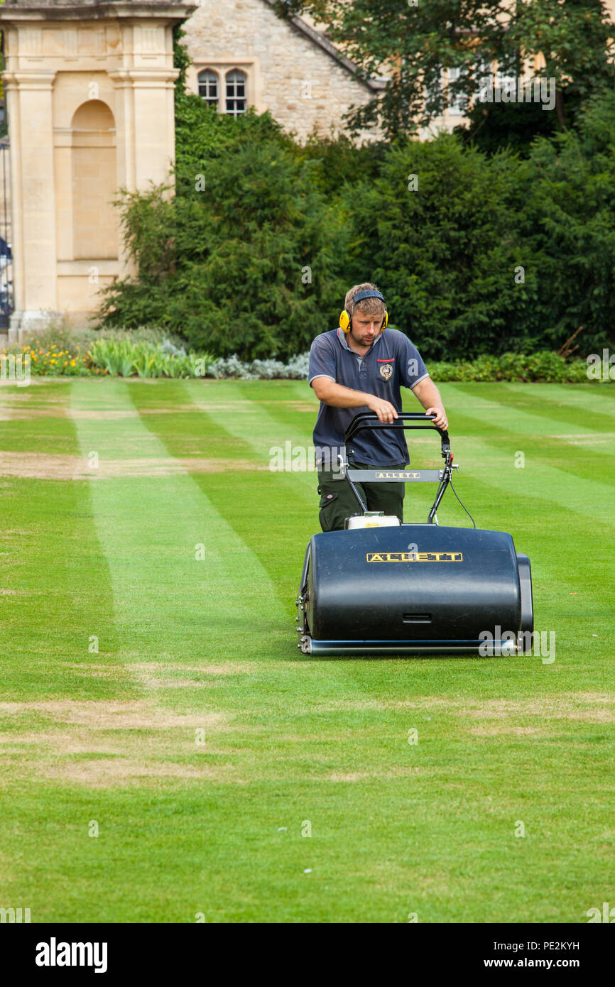 Giardiniere groundsman il taglio di falciare l'erba di prati al Trinity collage Oxford utilizzando un tradizionale Allett Buffalo 34' cilindro tosaerba Foto Stock