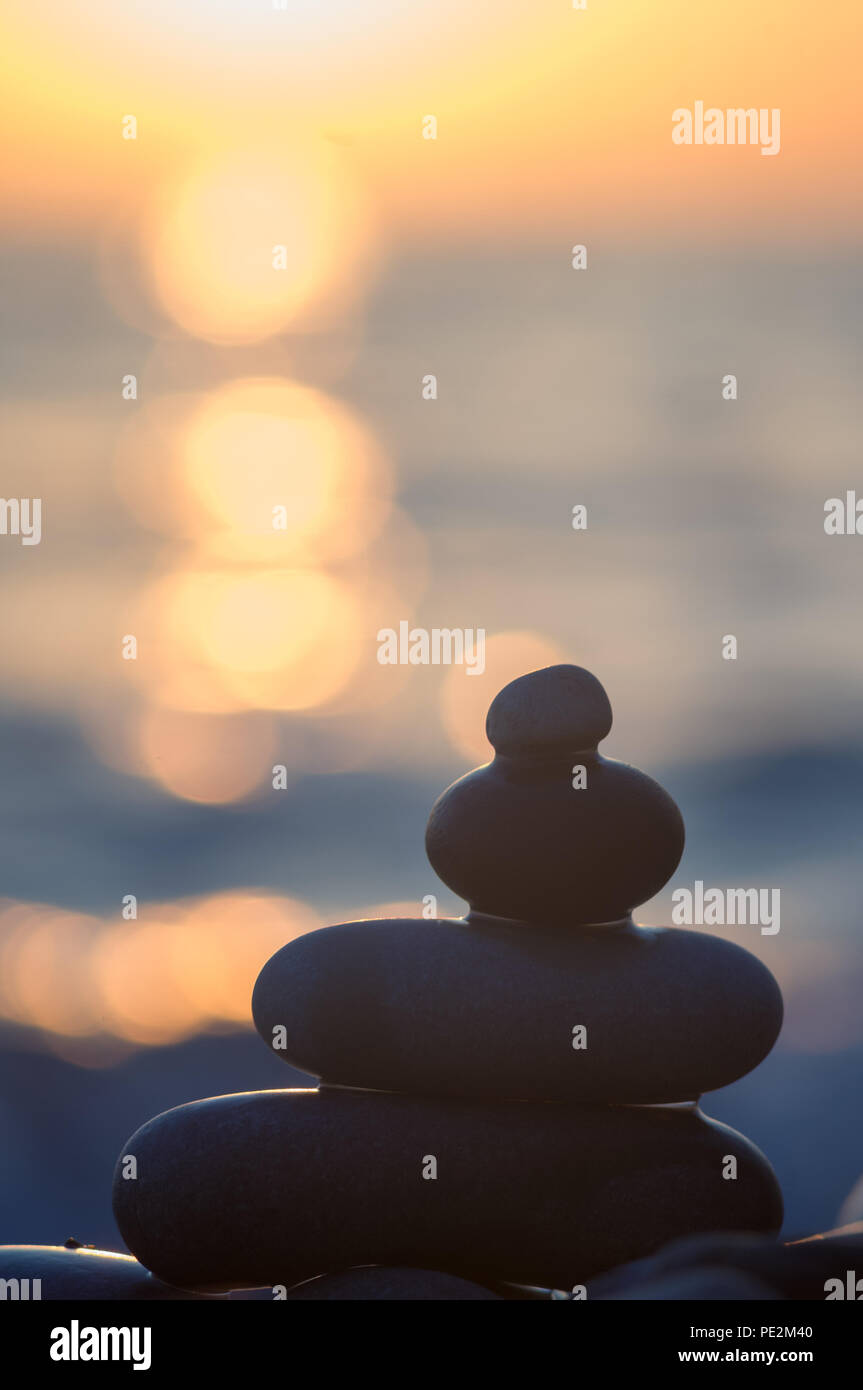 Piramide piegata Zen pietre ghiaia sul mare spiaggia al tramonto Foto Stock