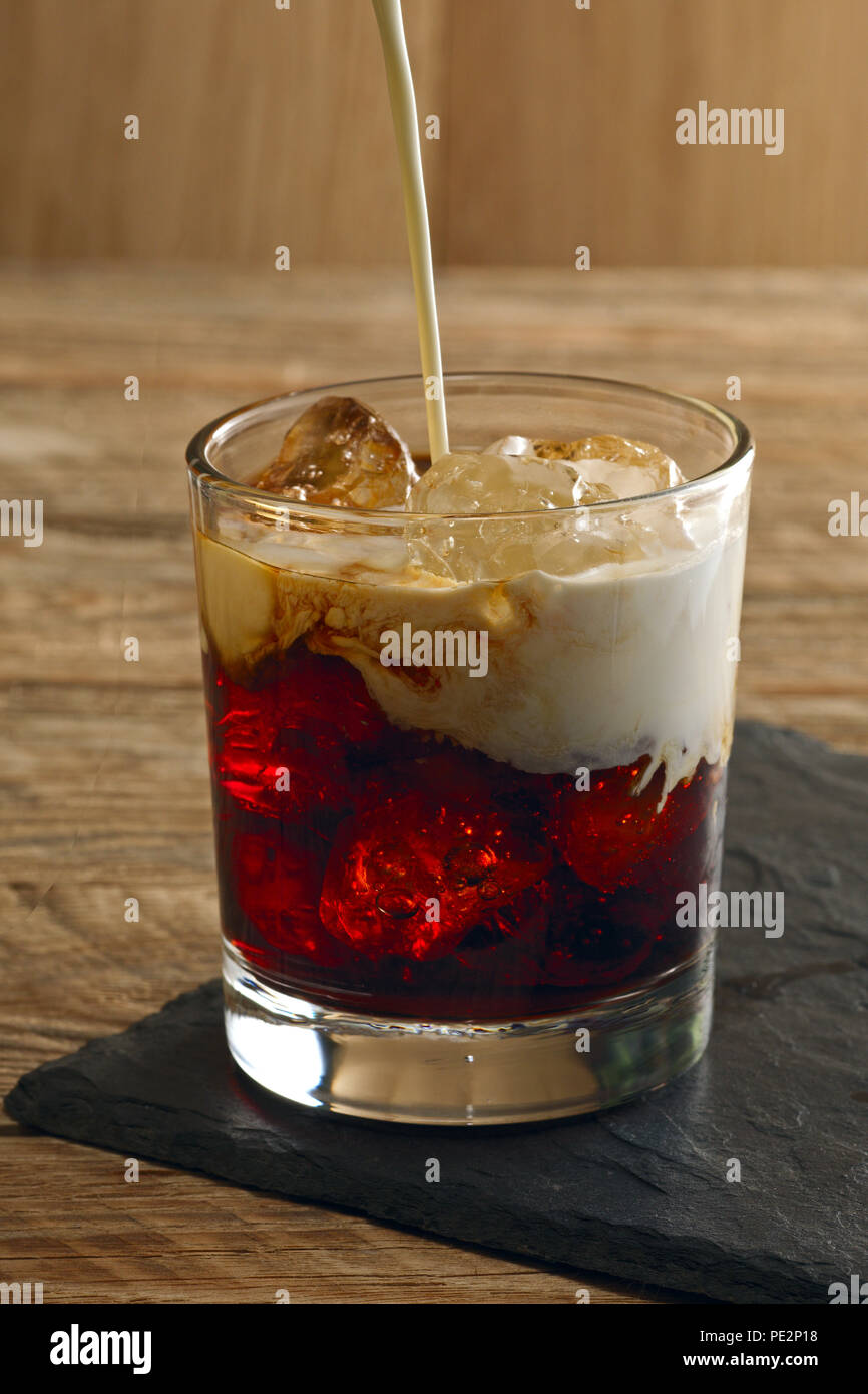 Versare la crema in cocktail White Russian. La vodka, il liquore al caffè, panna e ghiaccio Foto Stock