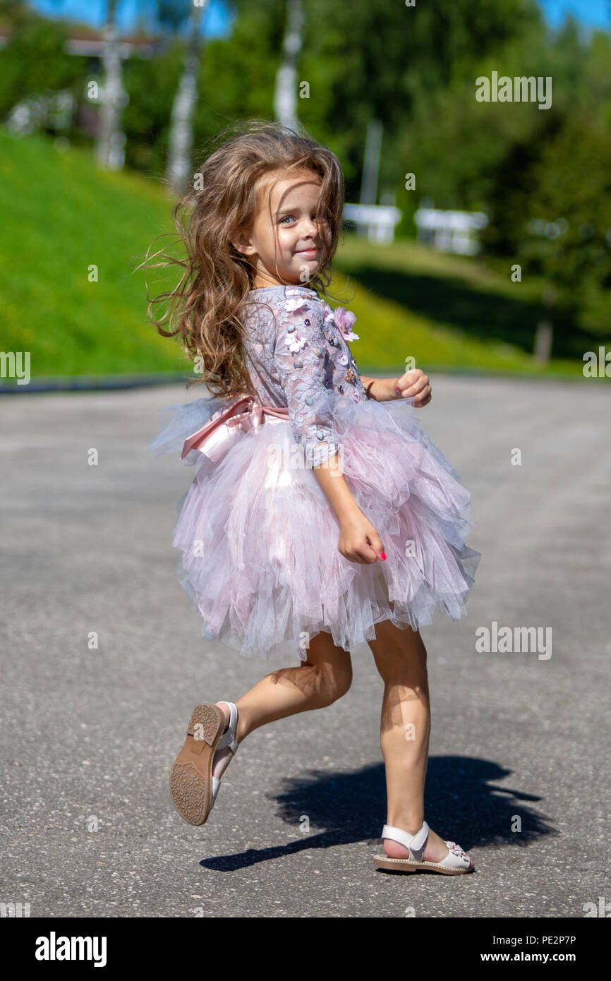 Ritratto di una bellissima bambina di lusso con capelli lunghi all'esterno. Esecuzione di bambino Foto Stock
