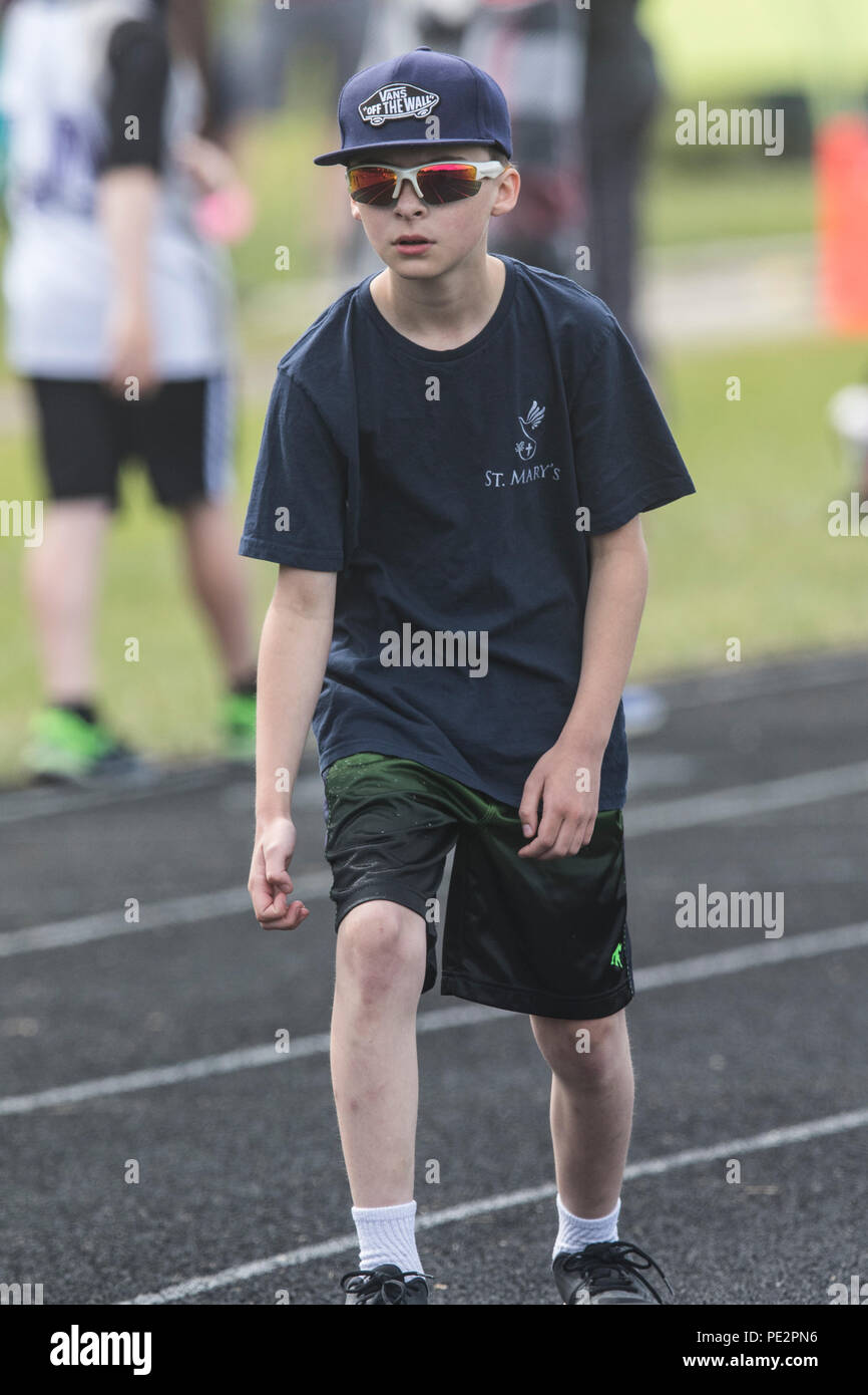 Giovane ragazzo in competizione in Track & Field, distanza di gara, sempre impostata su start, che indossa pantaloni corti e t-shirt,. Modello rilasciato Foto Stock