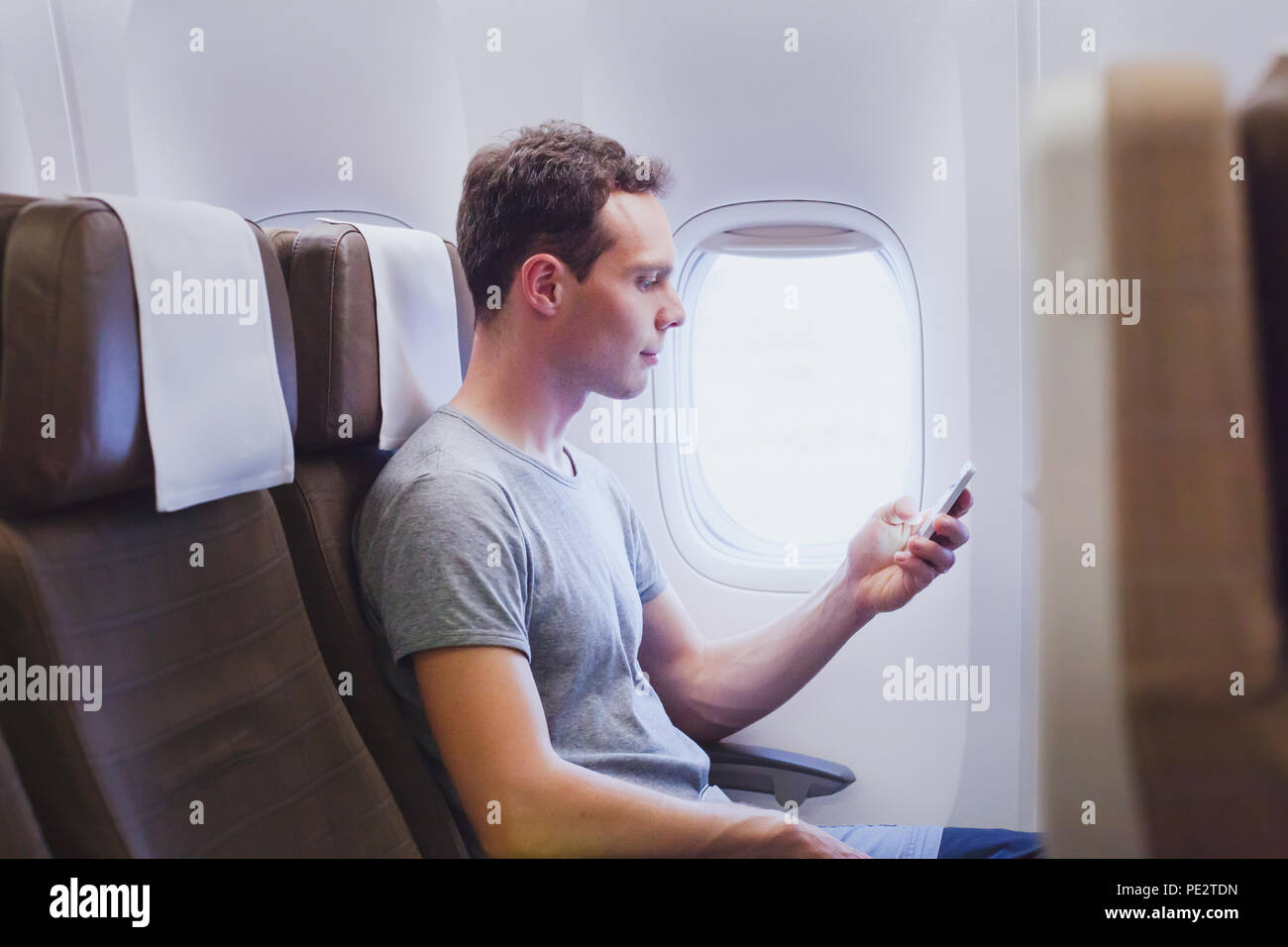 Passeggero di aereo utilizzando mobile smart phone nel piano, travel app sullo smartphone Foto Stock