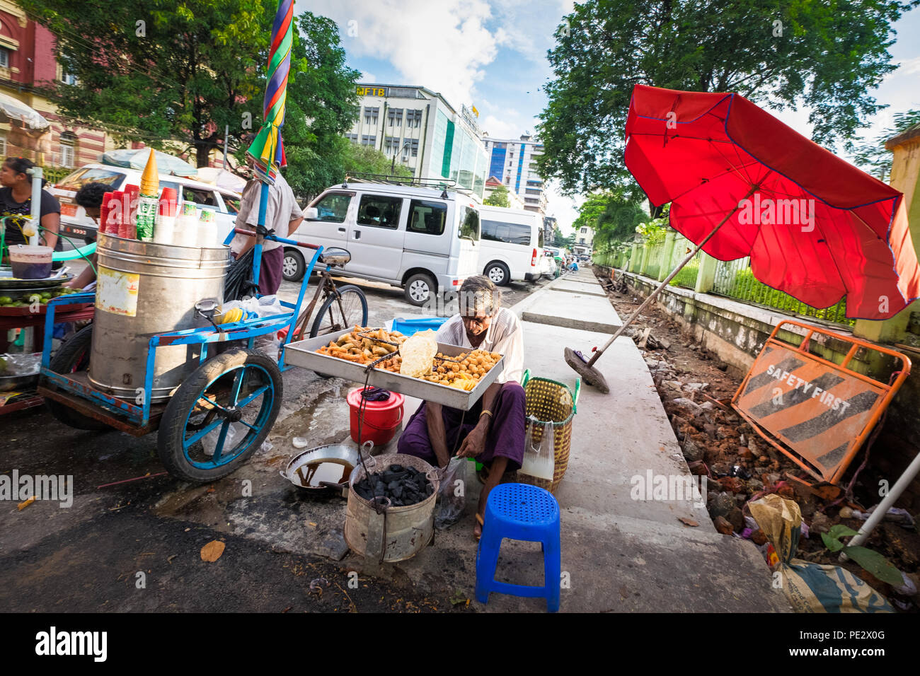 Un uomo vendita di una selezione di fritti snack di Yangon Foto Stock