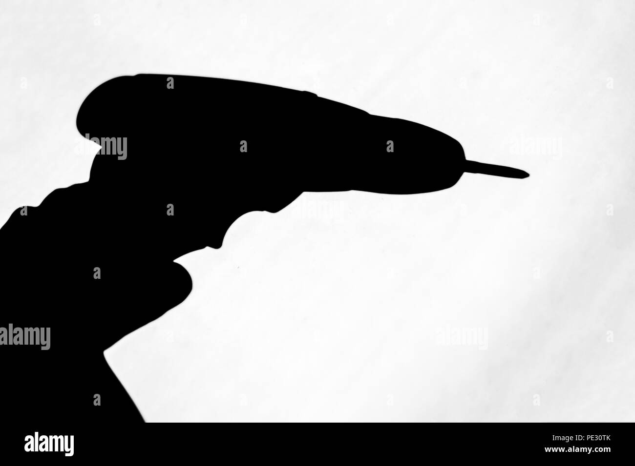 Isolato ombra nera di una mano che tiene un trapano Foto Stock