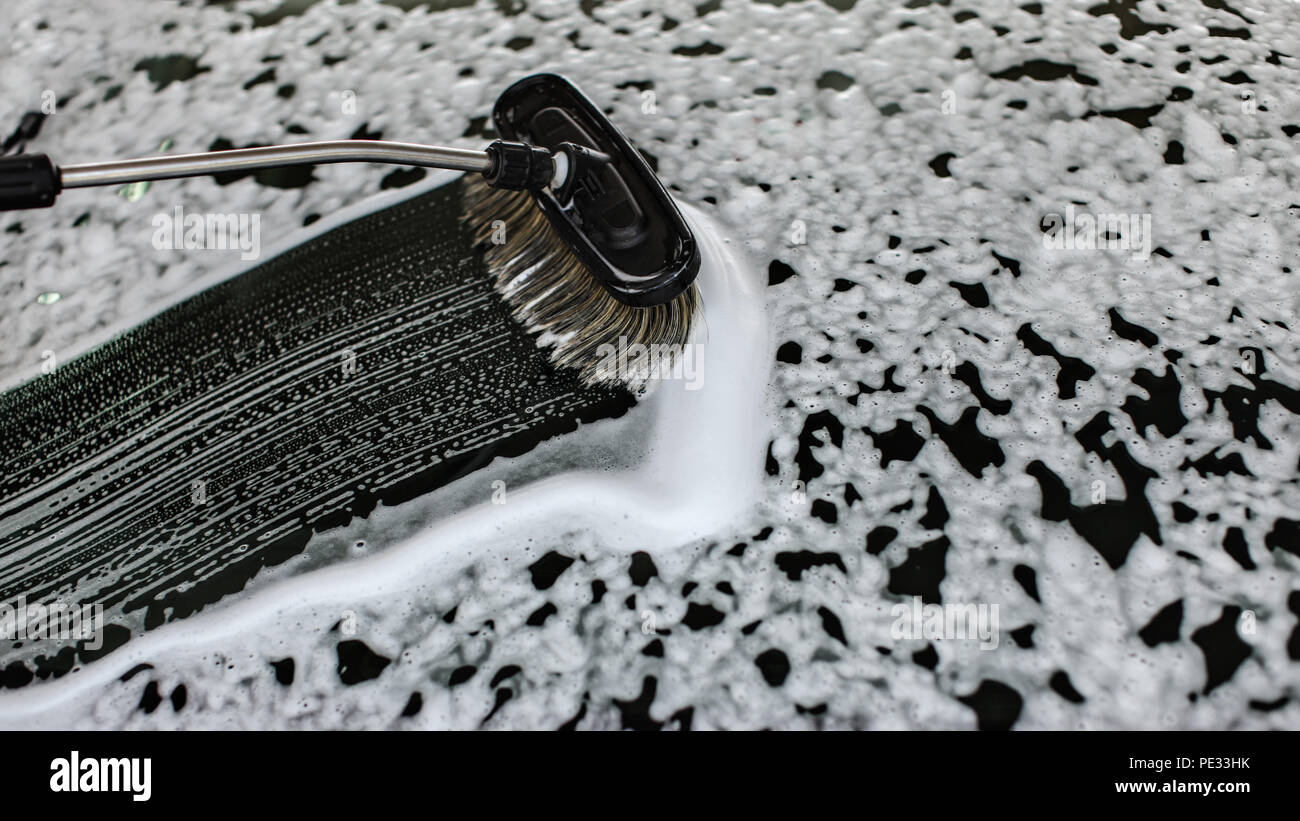 Pennello lasciando tratti nel sapone e schiuma sul vetro anteriore del vetro auto lavata al self service autolavaggi. Foto Stock