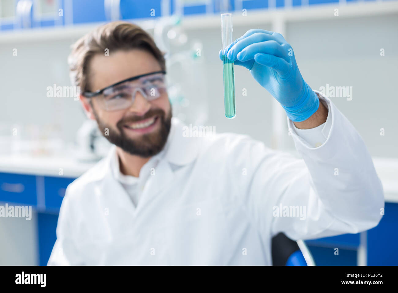 Reagente chimico. Messa a fuoco selettiva di provetta con blue liquido essendo in mani smart positivo scienziato maschio Foto Stock